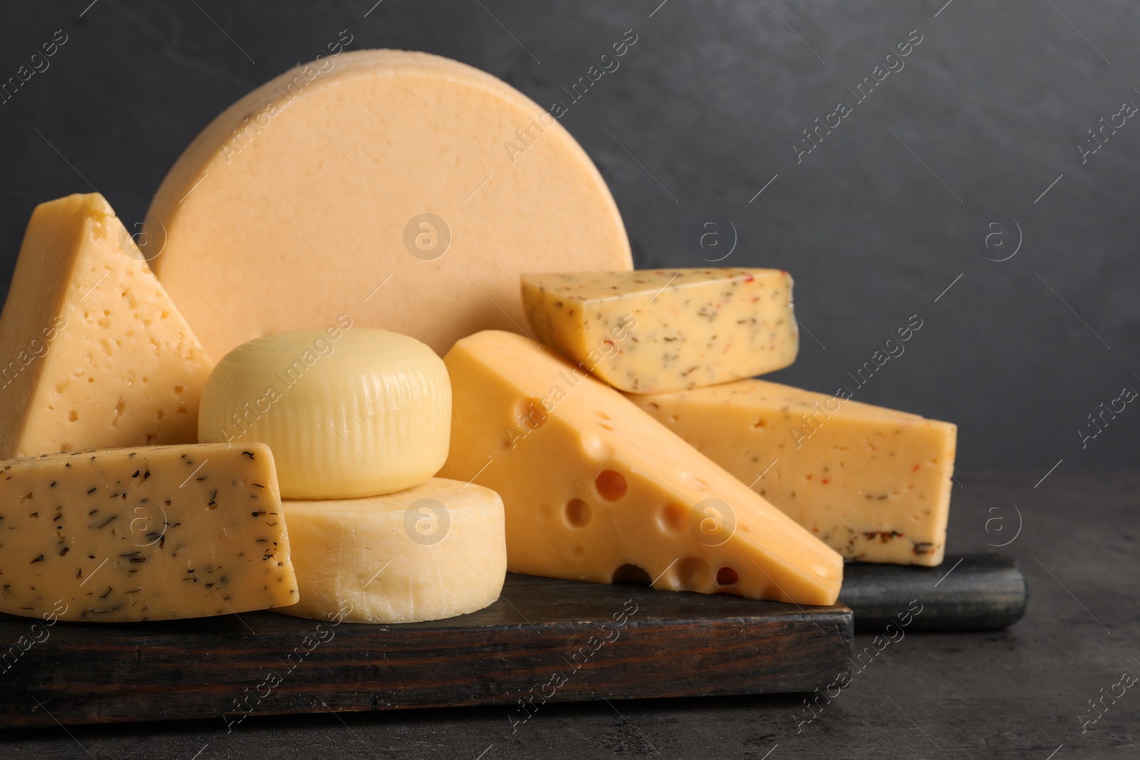 Photo of Wooden board with different sorts of cheese on grey table