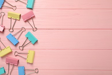 Photo of Colorful binder clips on pink wooden background, flat lay. Space for text