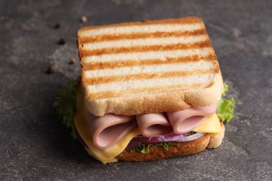 Photo of Delicious sandwich with boiled sausage, cheese and onion on grey textured table, closeup