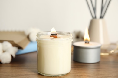 Photo of Burning candle with wooden wick on table