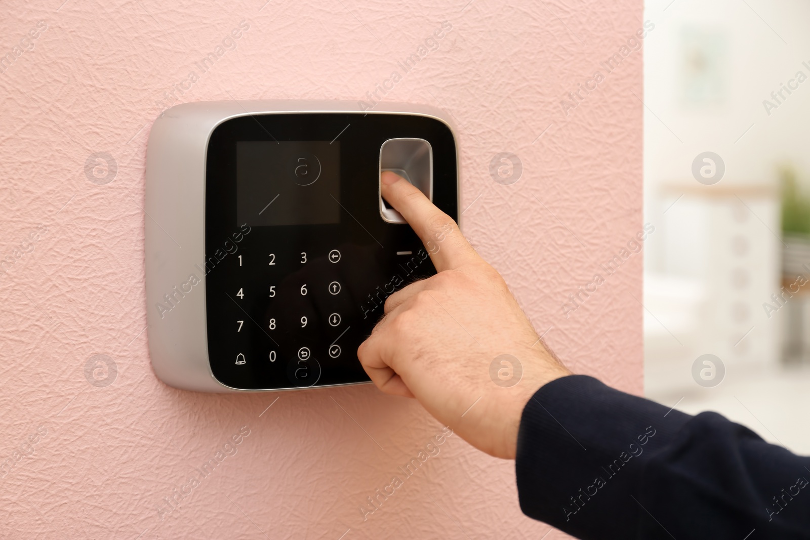 Photo of Man scanning fingerprint on alarm system at home, closeup
