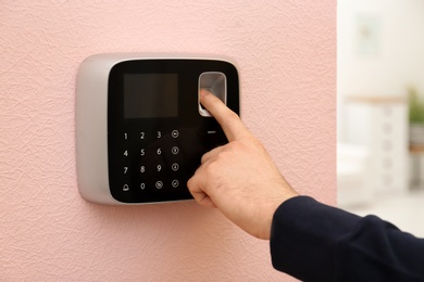 Man scanning fingerprint on alarm system at home, closeup