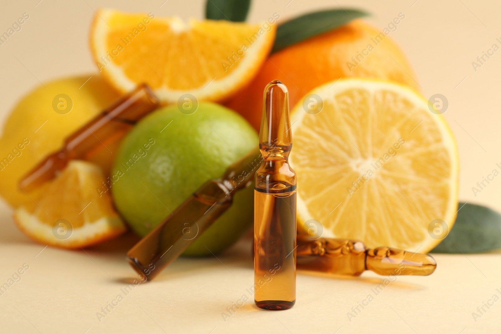 Photo of Skincare ampoules with vitamin C, different citrus fruits and leaves on beige background, closeup