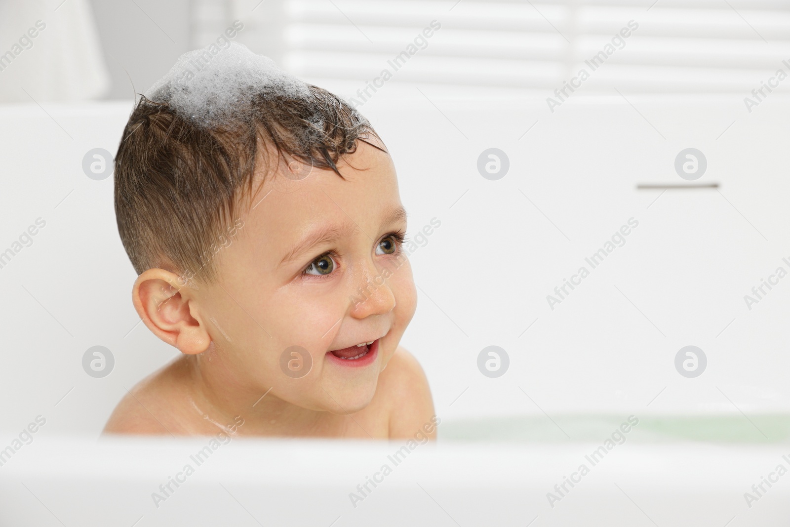 Photo of Cute little boy washing hair with shampoo in bathroom. Space for text