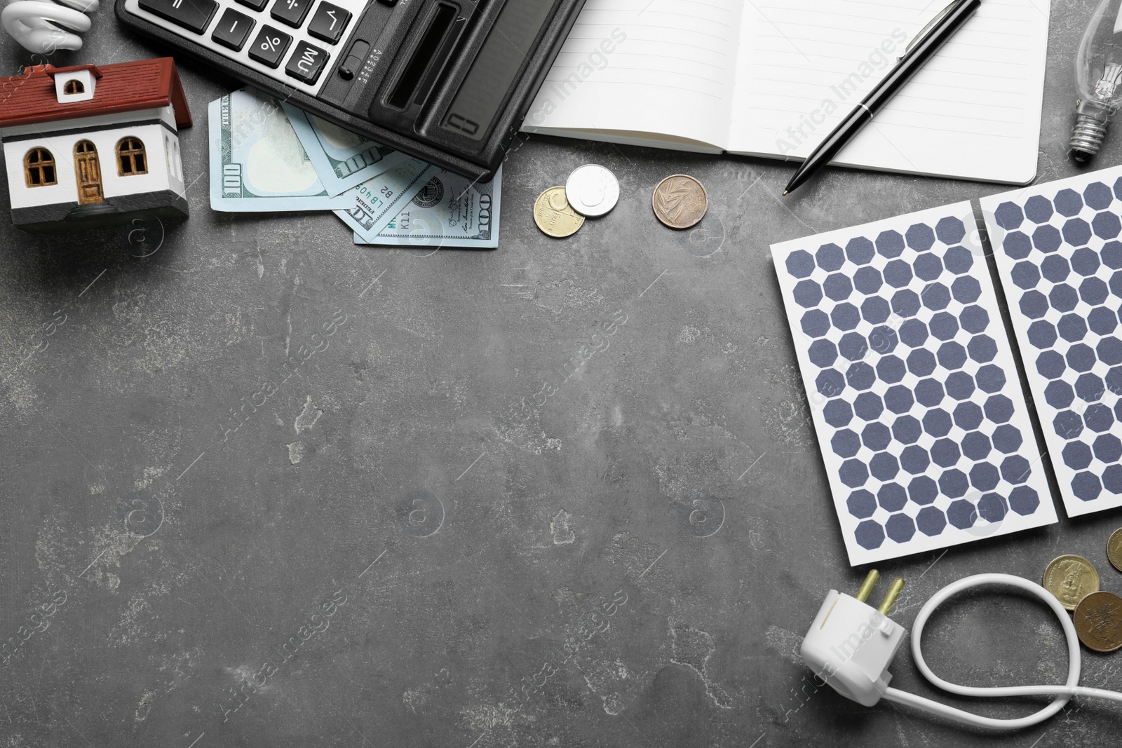 Photo of Flat lay composition with solar panels and house model on grey table. Space for text