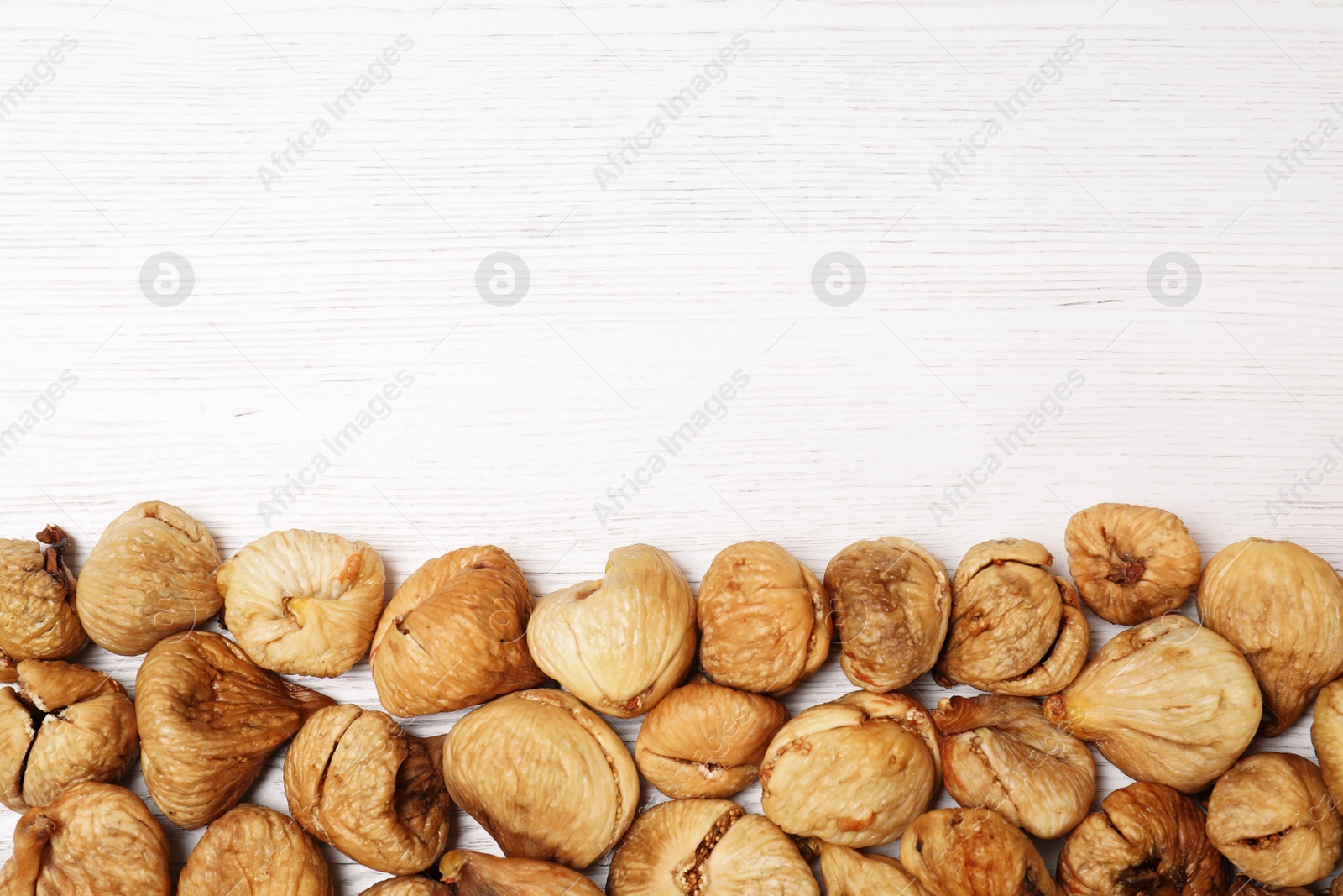 Photo of Dried figs on white wooden table, top view with space for text. Healthy fruit