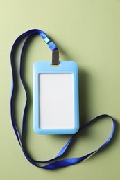 Photo of Blank light blue badge with string on green background, top view