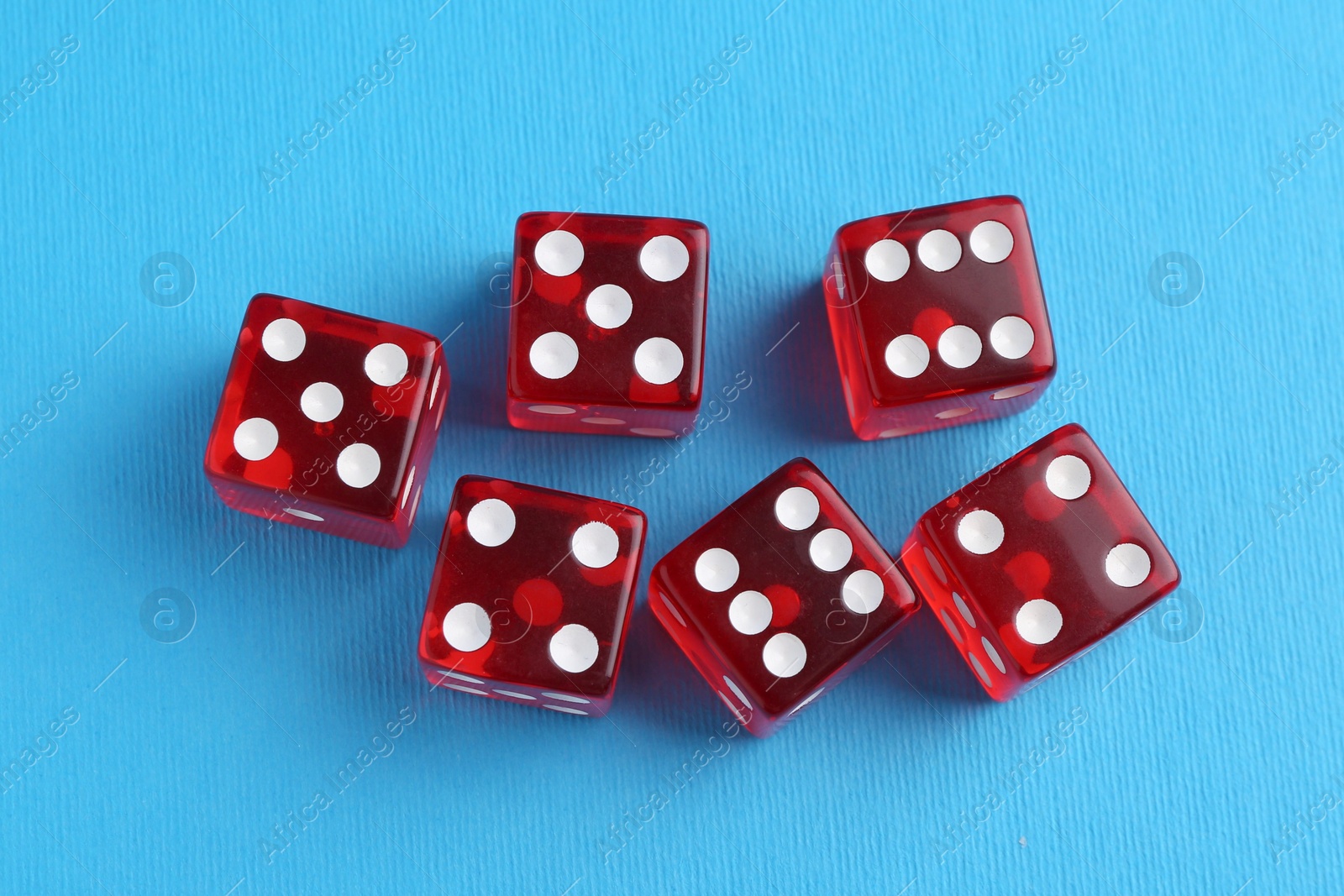 Photo of Many red game dices on light blue background, flat lay