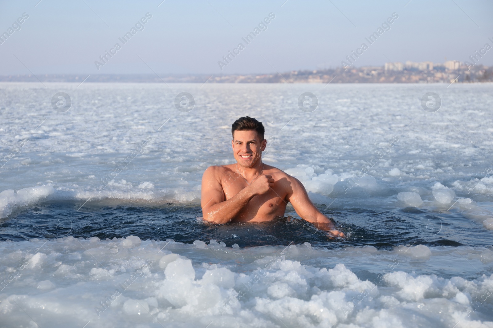 Photo of Man immersing in icy water on winter day. Baptism ritual