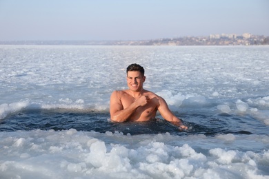 Man immersing in icy water on winter day. Baptism ritual