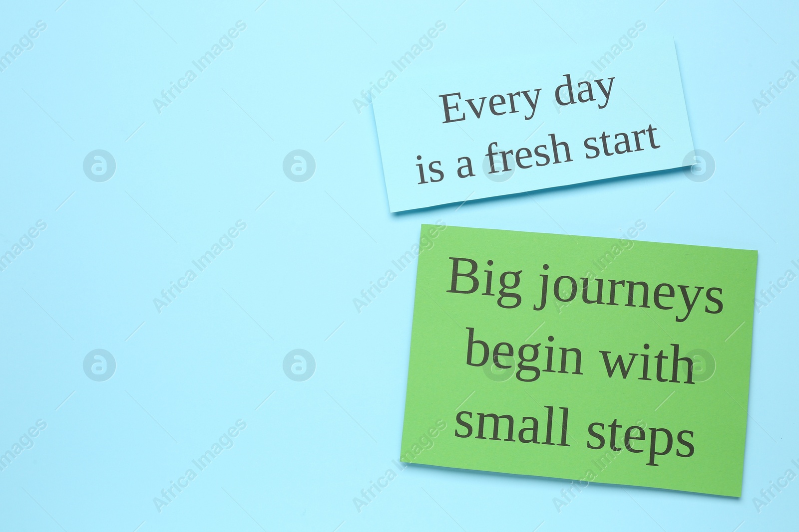 Photo of Notes with motivational quotes on light blue background, flat lay. Space for text