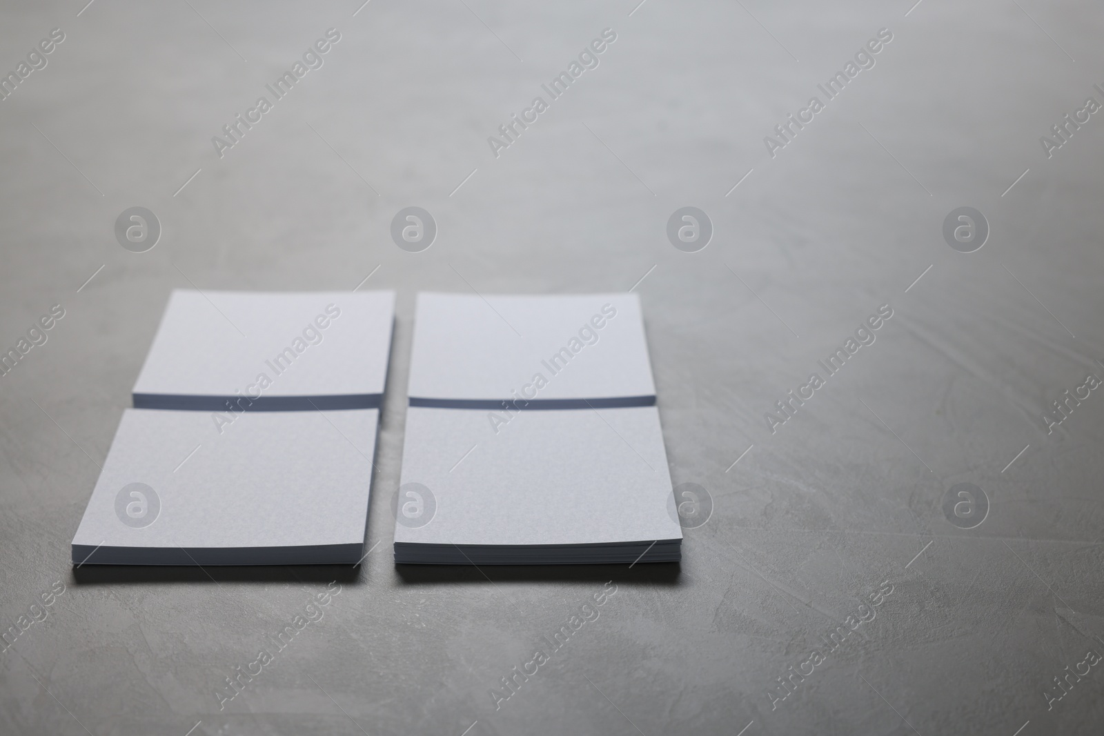 Photo of Blank paper sheets on grey textured table, closeup. Mockup for design