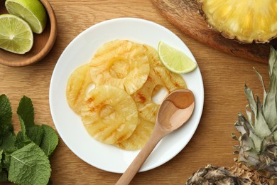 Photo of Tasty grilled pineapple slices, fresh lime and mint on wooden table, flat lay