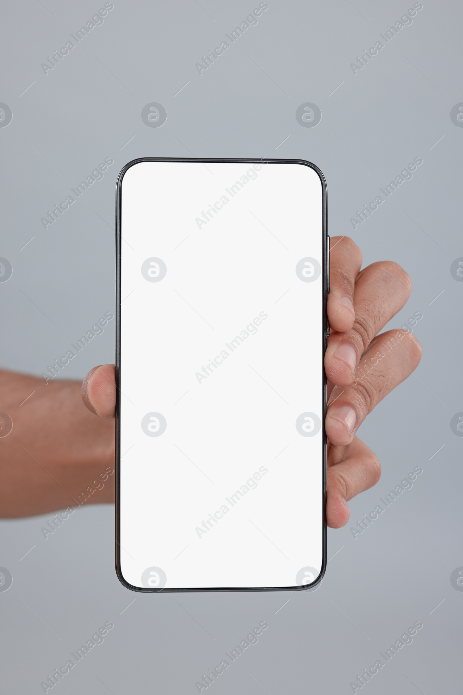 Photo of Man holding smartphone with blank screen on grey background, closeup