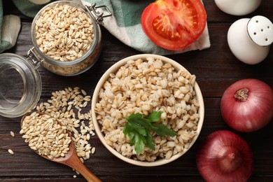 Photo of Delicious pearl barley served on wooden table, flat lay