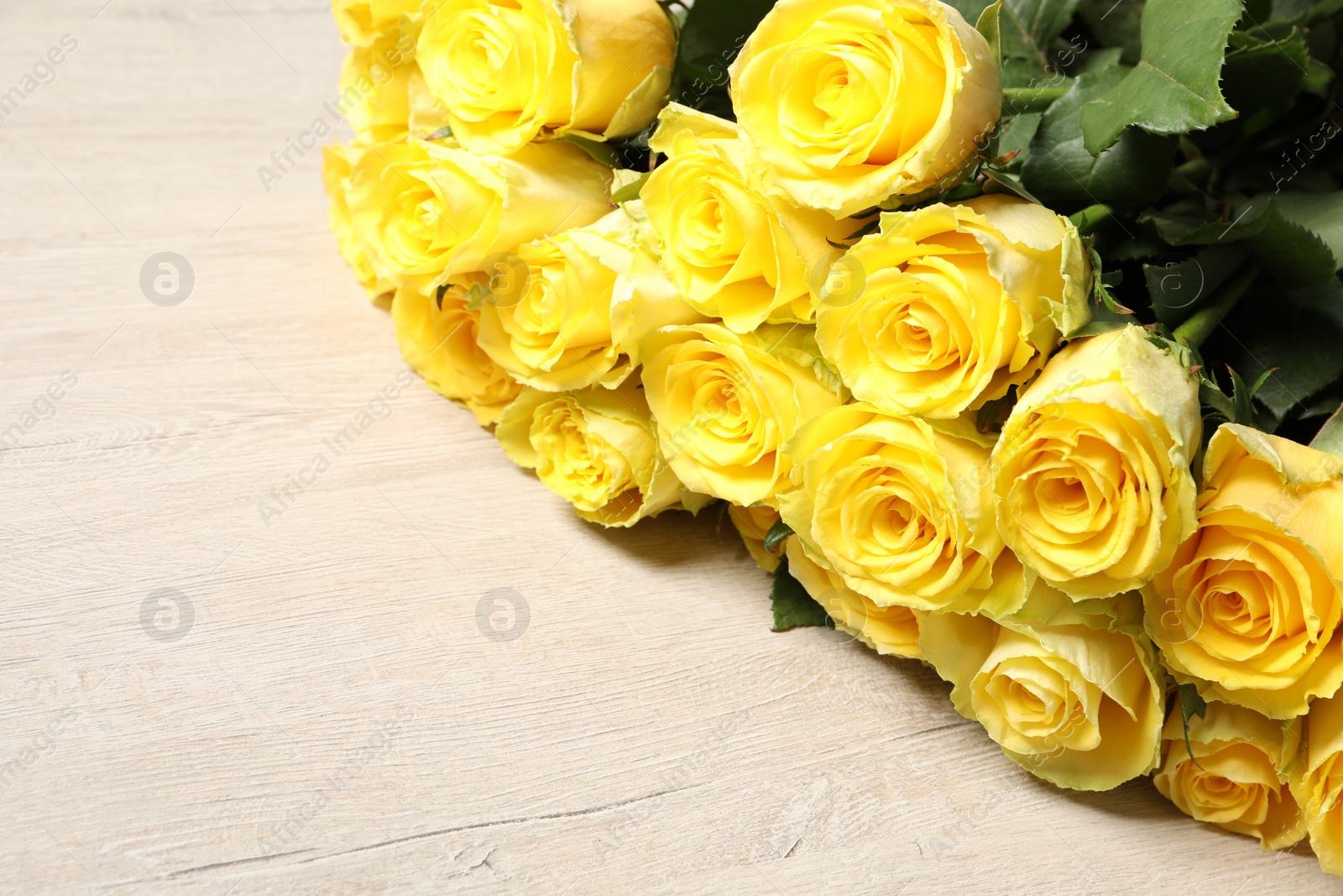 Photo of Beautiful bouquet of yellow roses on wooden table, space for text