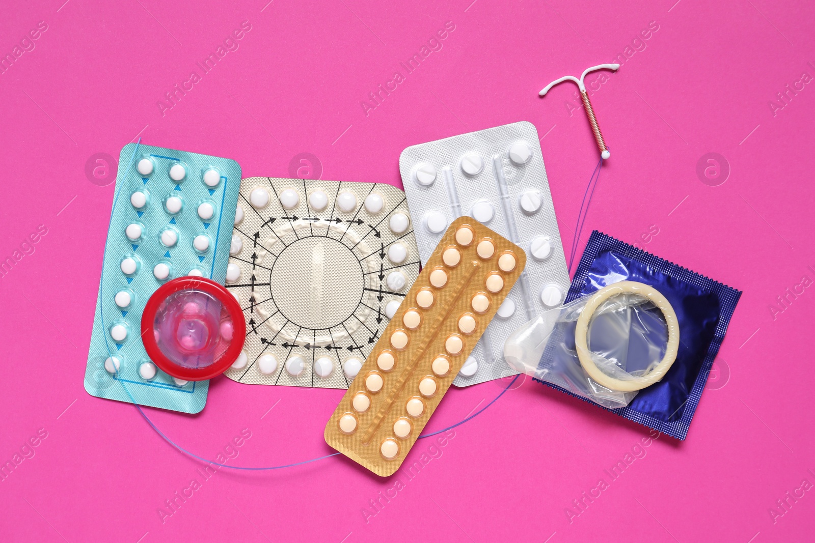 Photo of Contraceptive pills, condoms and intrauterine device on pink background, flat lay. Different birth control methods