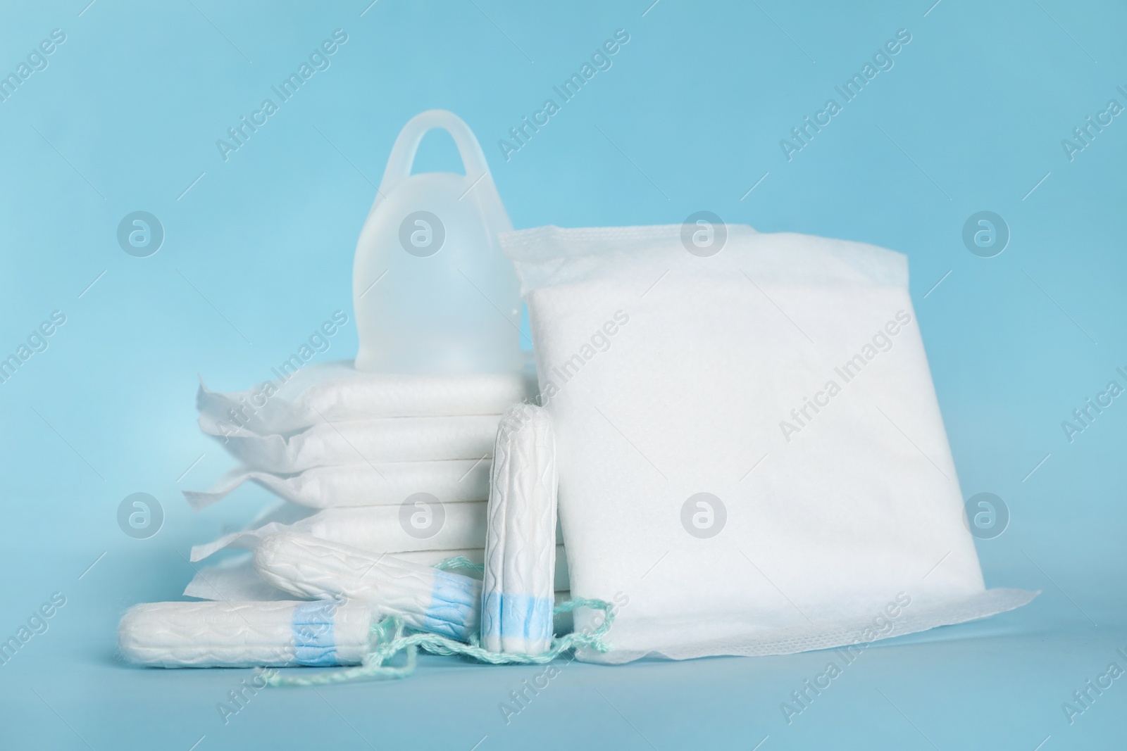 Photo of Menstrual pads and other hygiene products on light blue background