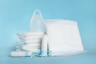 Photo of Menstrual pads and other hygiene products on light blue background