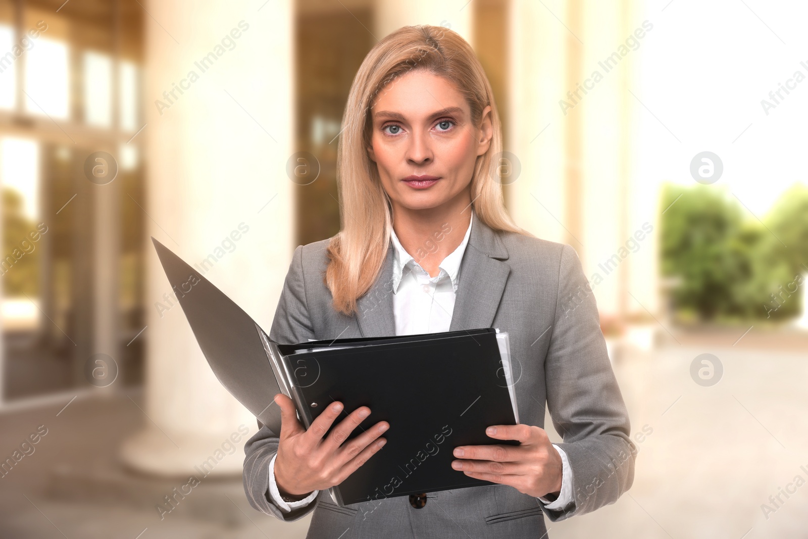 Image of Lawyer, consultant, business owner. Confident woman with file folders outdoors