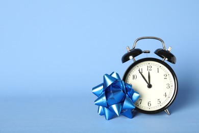 Photo of Vintage alarm clock with Christmas decor on light blue background, space for text. New Year countdown