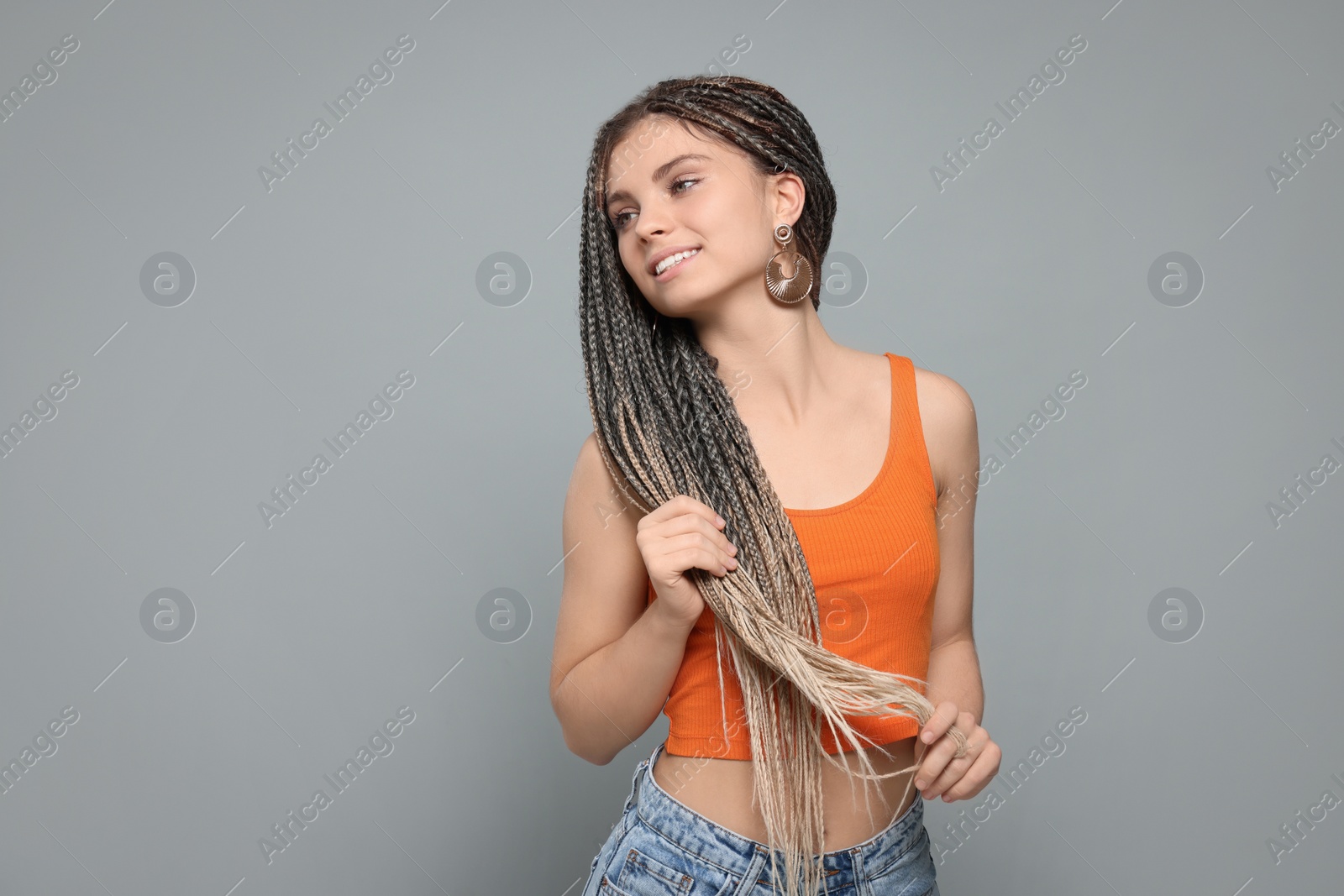 Photo of Beautiful woman with long african braids on grey background, space for text