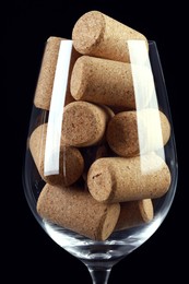 Photo of Glass full of wine corks on black background, closeup