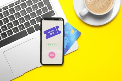 Photo of Smartphone with activated promo code, credit card and laptop on yellow background, flat lay