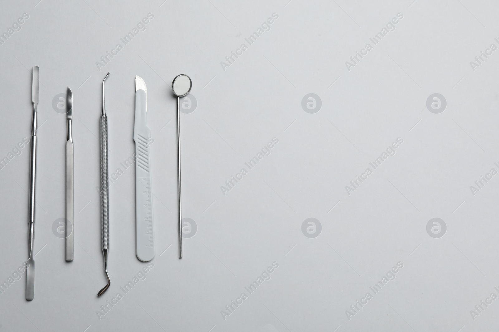 Photo of Set of different dentist's tools on light grey background, flat lay. Space for text