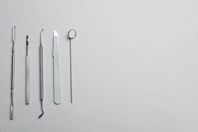 Photo of Set of different dentist's tools on light grey background, flat lay. Space for text