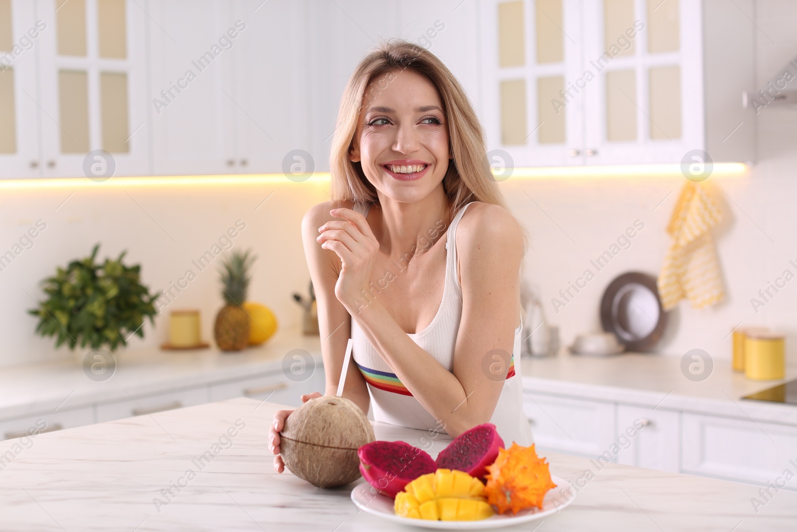 Photo of Young woman with exotic fruits in kitchen