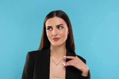 Beautiful woman with elegant necklace on light blue background