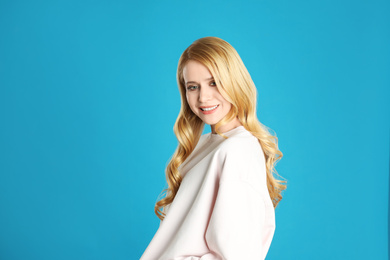 Portrait of beautiful young woman with dyed long hair on blue background