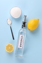 Photo of Eco friendly natural cleaners. Vinegar in bottle, soda and lemons on light blue background, flat lay