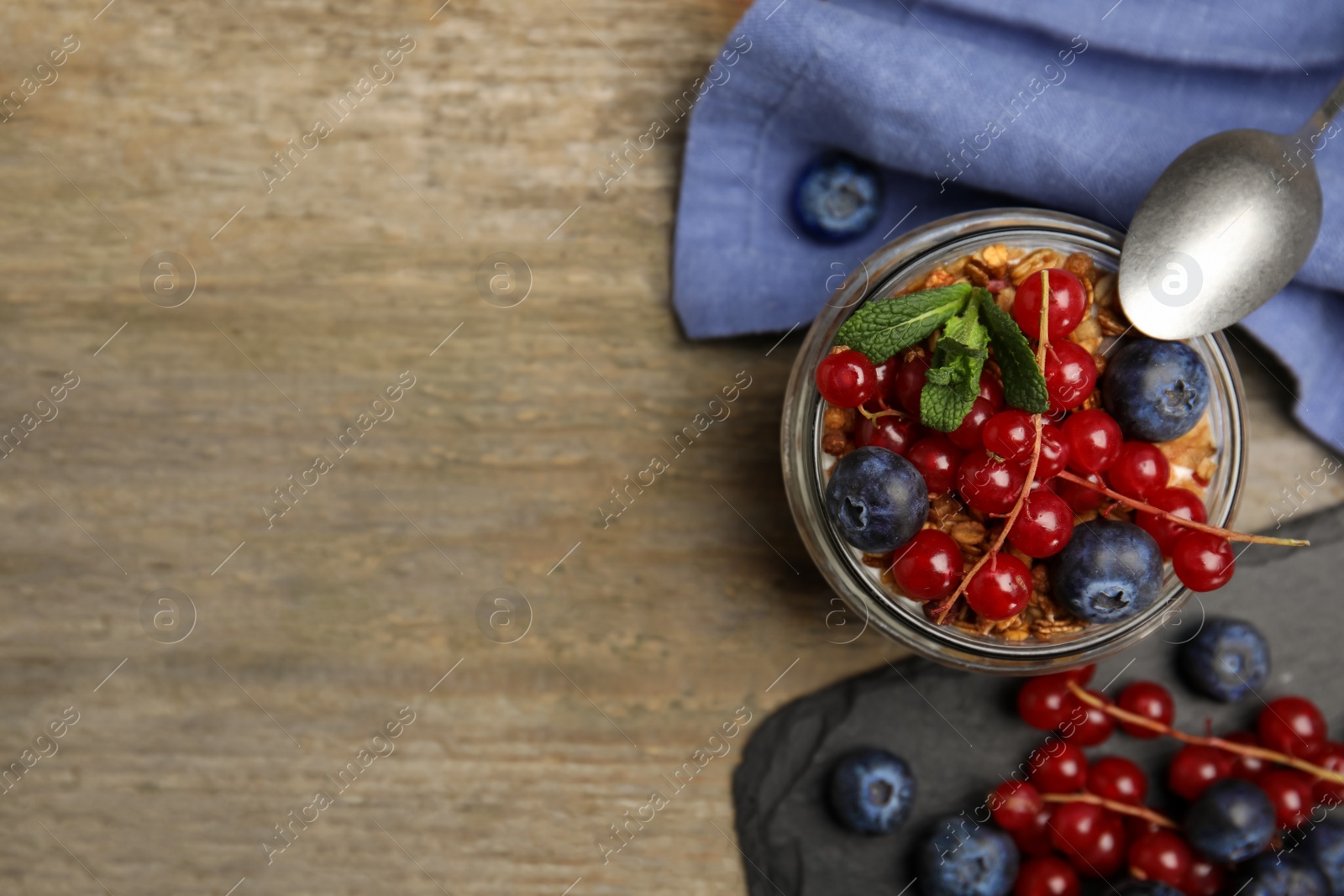 Photo of Delicious yogurt parfait with fresh berries and mint on wooden table, flat lay. Space for text