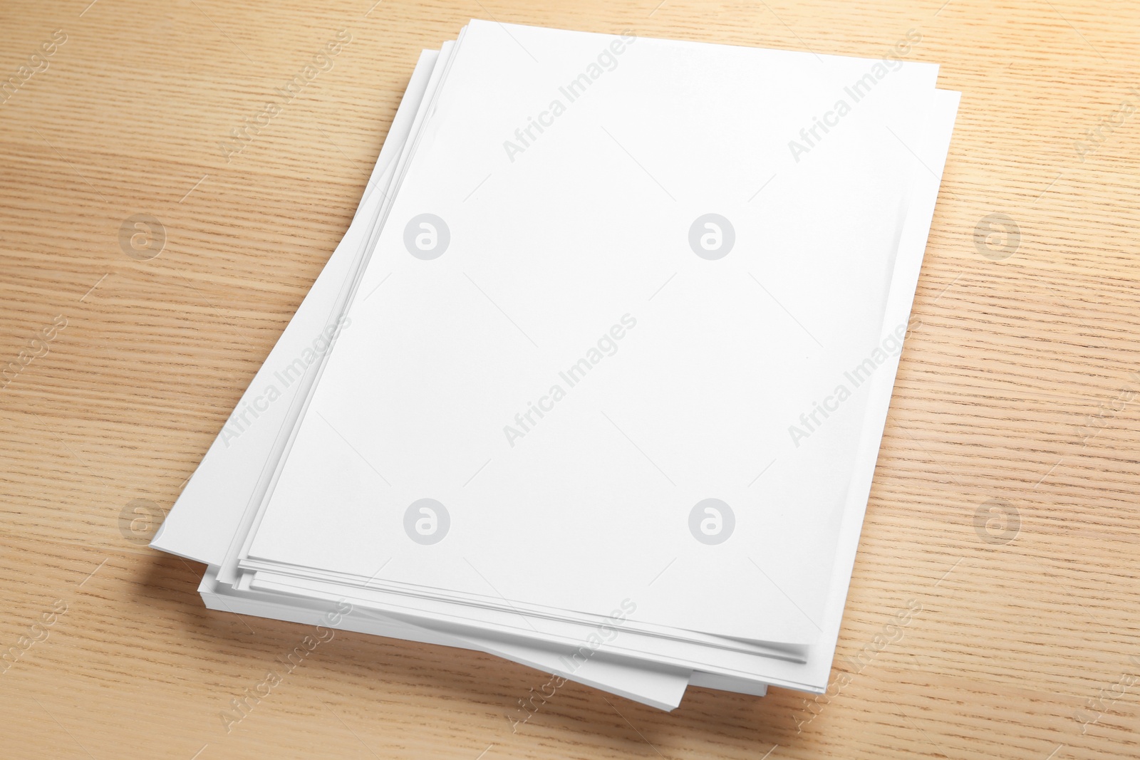 Photo of Stack of blank paper sheets for brochure on wooden background. Mock up