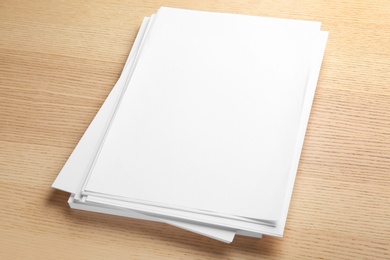 Stack of blank paper sheets for brochure on wooden background. Mock up