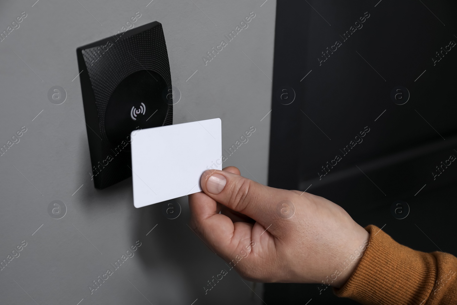 Photo of Man opening magnetic door lock with key card, closeup. Home security