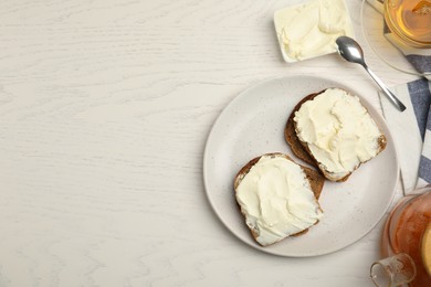 Photo of Bread with cream cheese on white wooden table, flat lay. Space for text