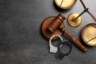 Photo of Judge's gavel, handcuffs and scales on grey background, flat lay with space for text. Criminal law concept