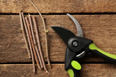 Secateur with wooden twigs on table, flat lay