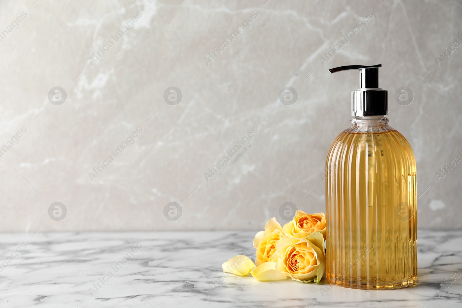 Photo of Stylish dispenser with liquid soap and beautiful flowers on white marble table, space for text