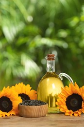 Sunflower cooking oil, seeds and yellow flowers on wooden table outdoors, space for text