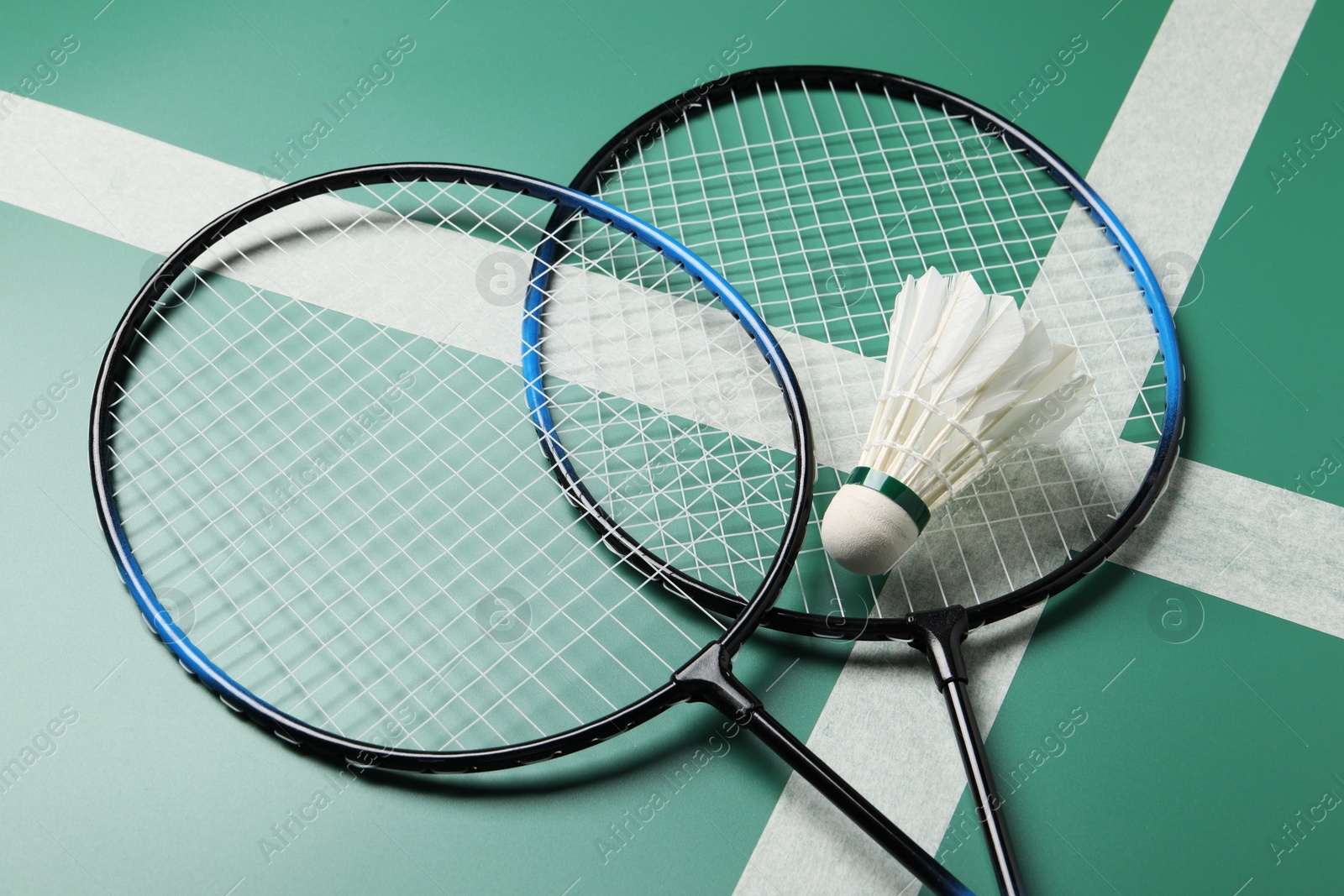 Photo of Feather badminton shuttlecock and rackets on green table, closeup