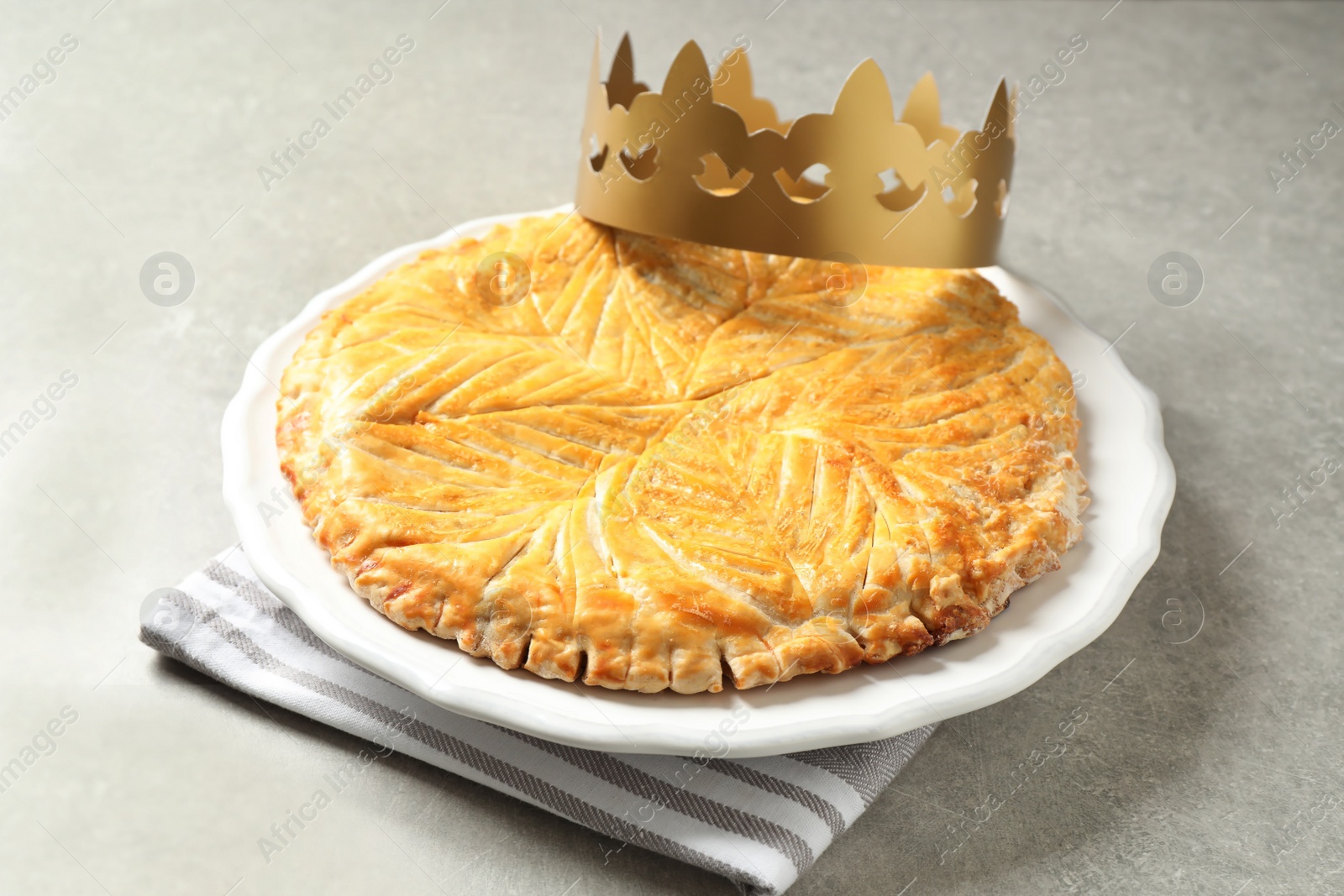 Photo of Traditional galette des Rois with paper crown on light grey table