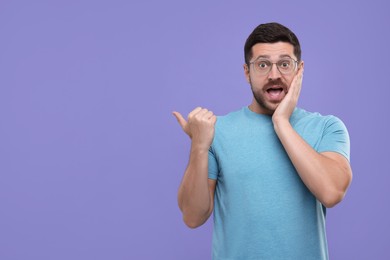 Special promotion. Emotional man pointing at something on purple background. Space for text
