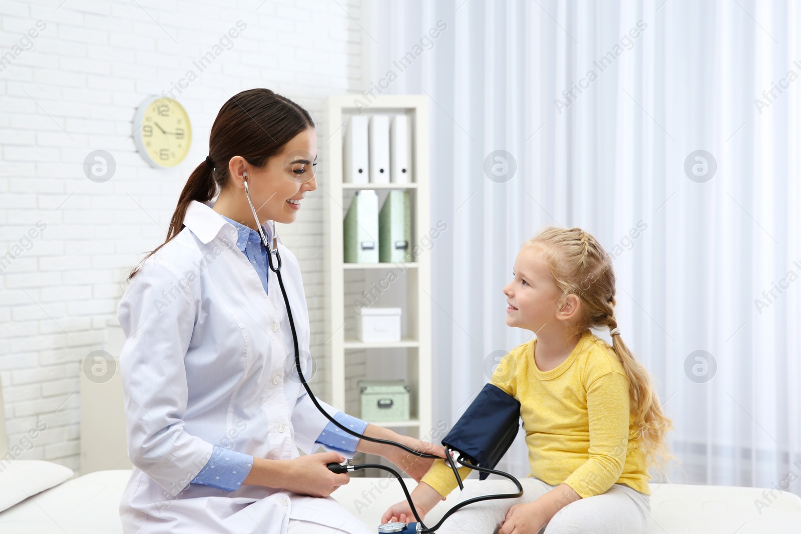 Photo of Little girl visiting doctor in hospital. Measuring blood pressure and checking pulse