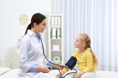 Little girl visiting doctor in hospital. Measuring blood pressure and checking pulse