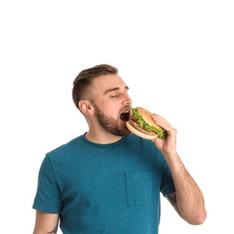 Young man eating tasty burger on white background