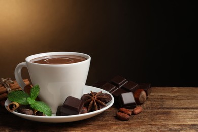 Photo of Yummy hot chocolate in cup on wooden table, space for text